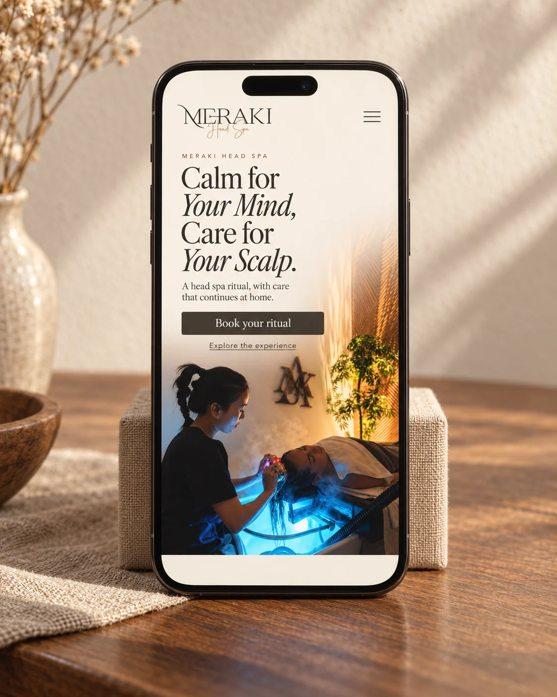 Meraki Head Spa mobile website design concept shown on a phone in a warmly lit setting.